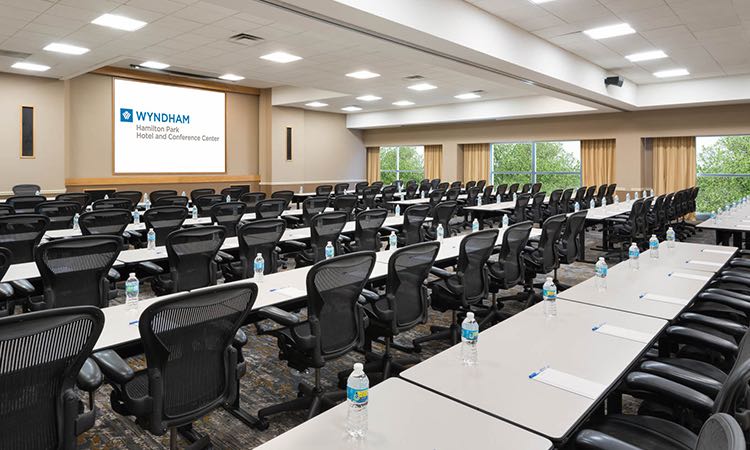 Large room with rows of tables with chairs facing projection screen