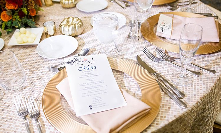 Table set for wedding reception with invitation on gold plate