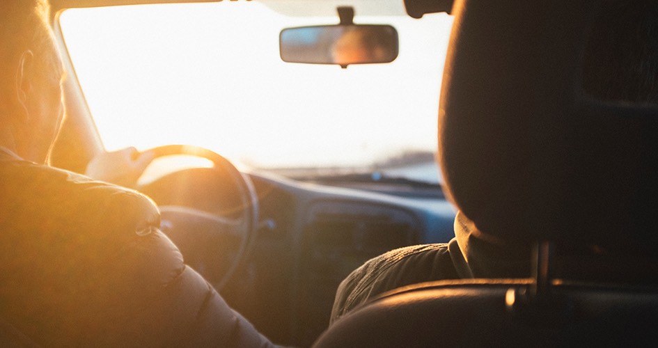 man driving car into the sunset