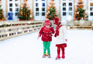 two kids hold hands while ice skating
