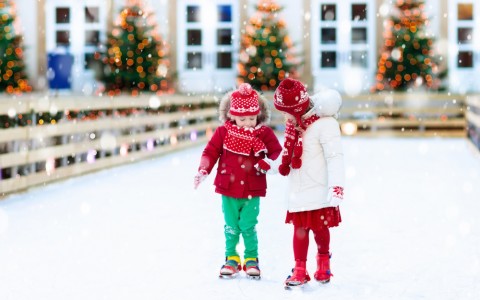 two kids hold hands while ice skating