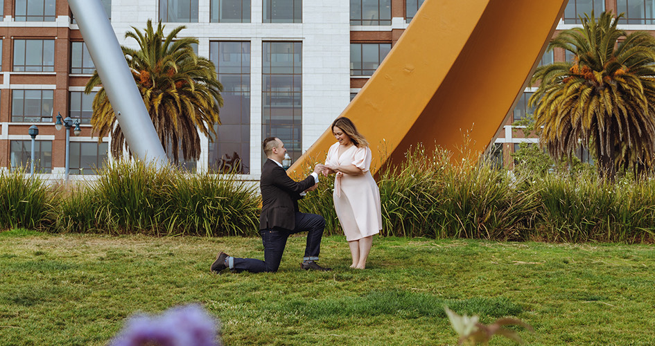 couple getting engaged in a park with surrounding installation art