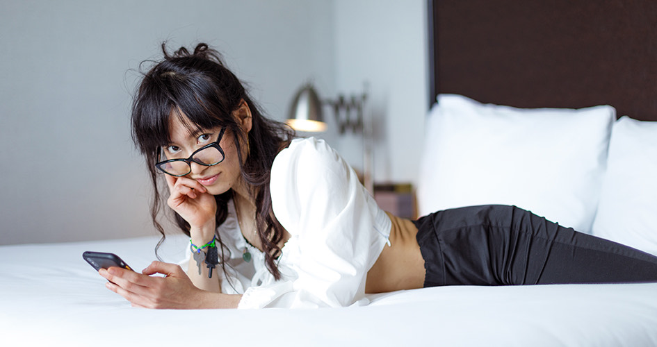 girl laying on hotel bed looking into camera