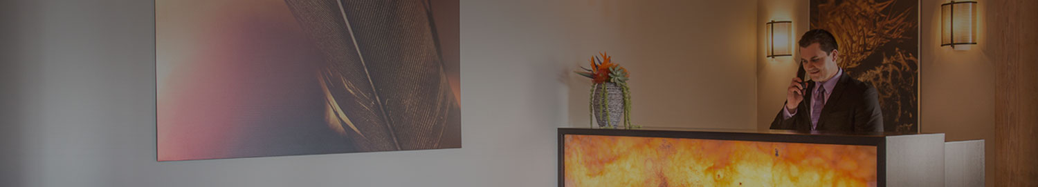A man talking on the phone at the reception desk with a large painting on the wall next to him