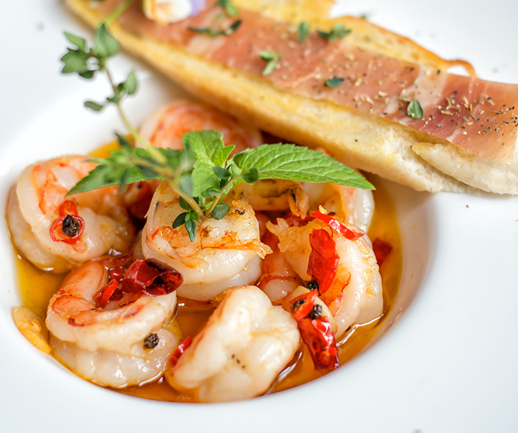 shrimp in a broth in a bowl with bread on the side