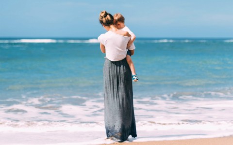 mother and child standing near the ocean