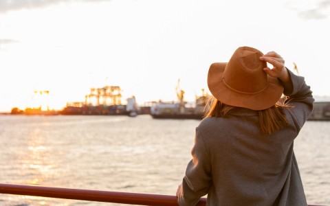 single woman with tan hat looking over the marina