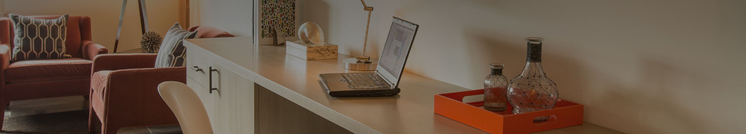Desk area with a laptop, lamp, tray of decorative bottles, and two chairs in the back corner