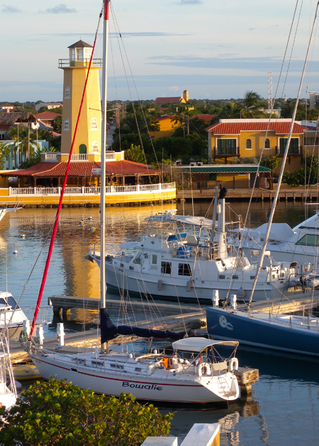 marina with multiple colorful yachts and a lighthouse in the back