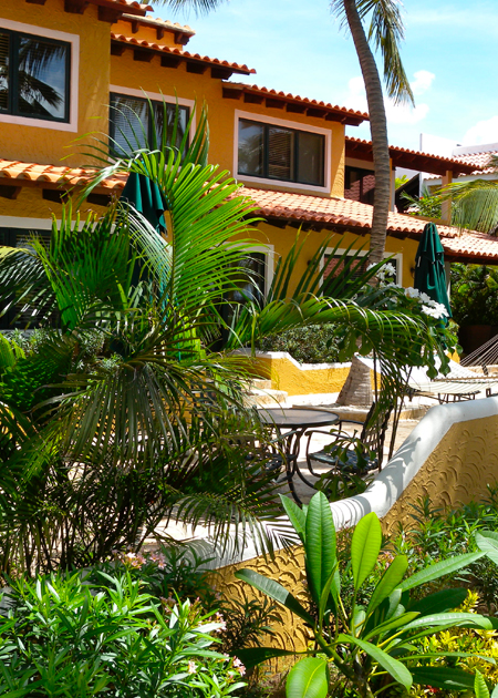 exterior of yellow building with lush palm trees
