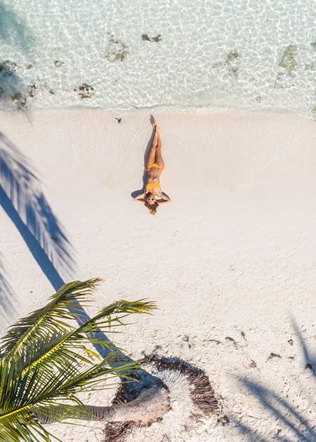 aerial view of woman with bathing suit laying on the sand by the waves