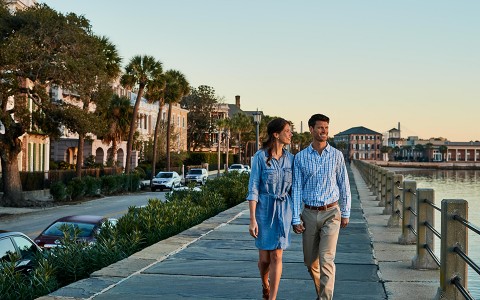 a couple walking hand in hand down a harborfront