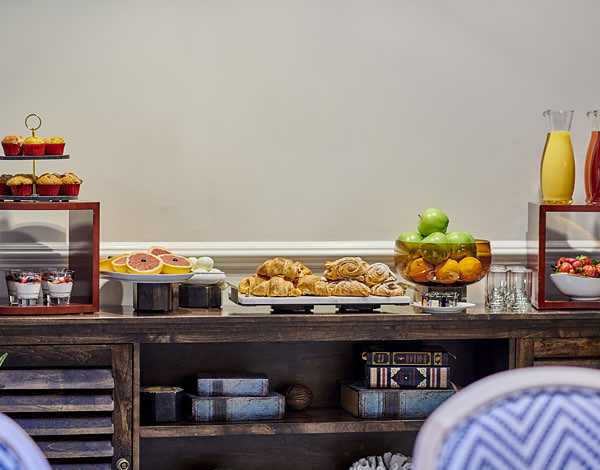 view of breakfast buffet featuring various croissants, muffins, fruits and fruit juices
