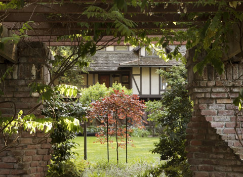 little nook in the gardens with twisting brickwork underneath a vine covered pergola 