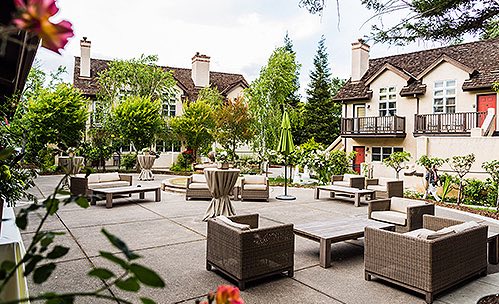 Outdoor terrace with cushioned wicker seating & cottages with chimneys in the back