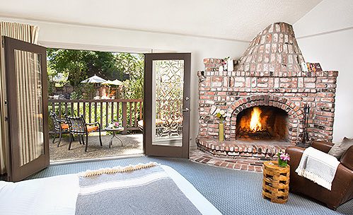 Room with brick fireplace and metallic seating on patio