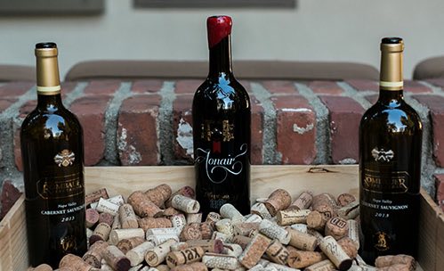 Three wine bottle surrounded by corks
