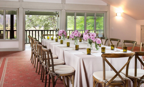 A long table with wooden chairs set up for a dinner reception