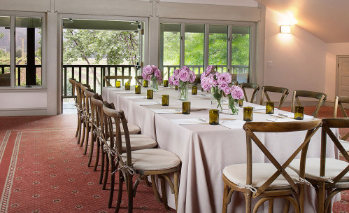 Long rectangular table with chairs & purple flower arrangements