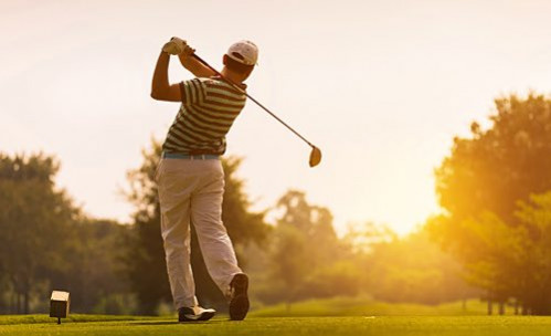 man playing golf at sunset