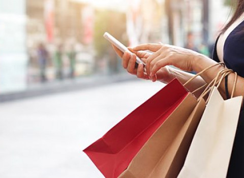 woman holding shopping bags using her phone