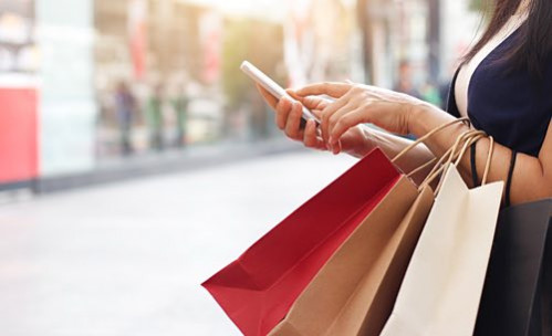 woman holding shopping bags using her phone
