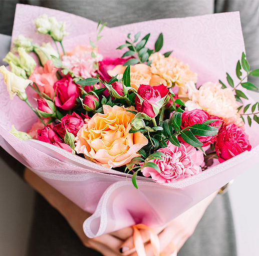 woman holding bouquet of pink carnations and roses