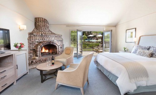 suite room with king bed and fireplace with a pool view 