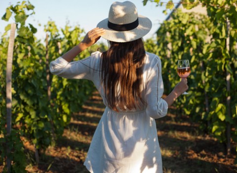 woman holding a glass of wine in vineyard