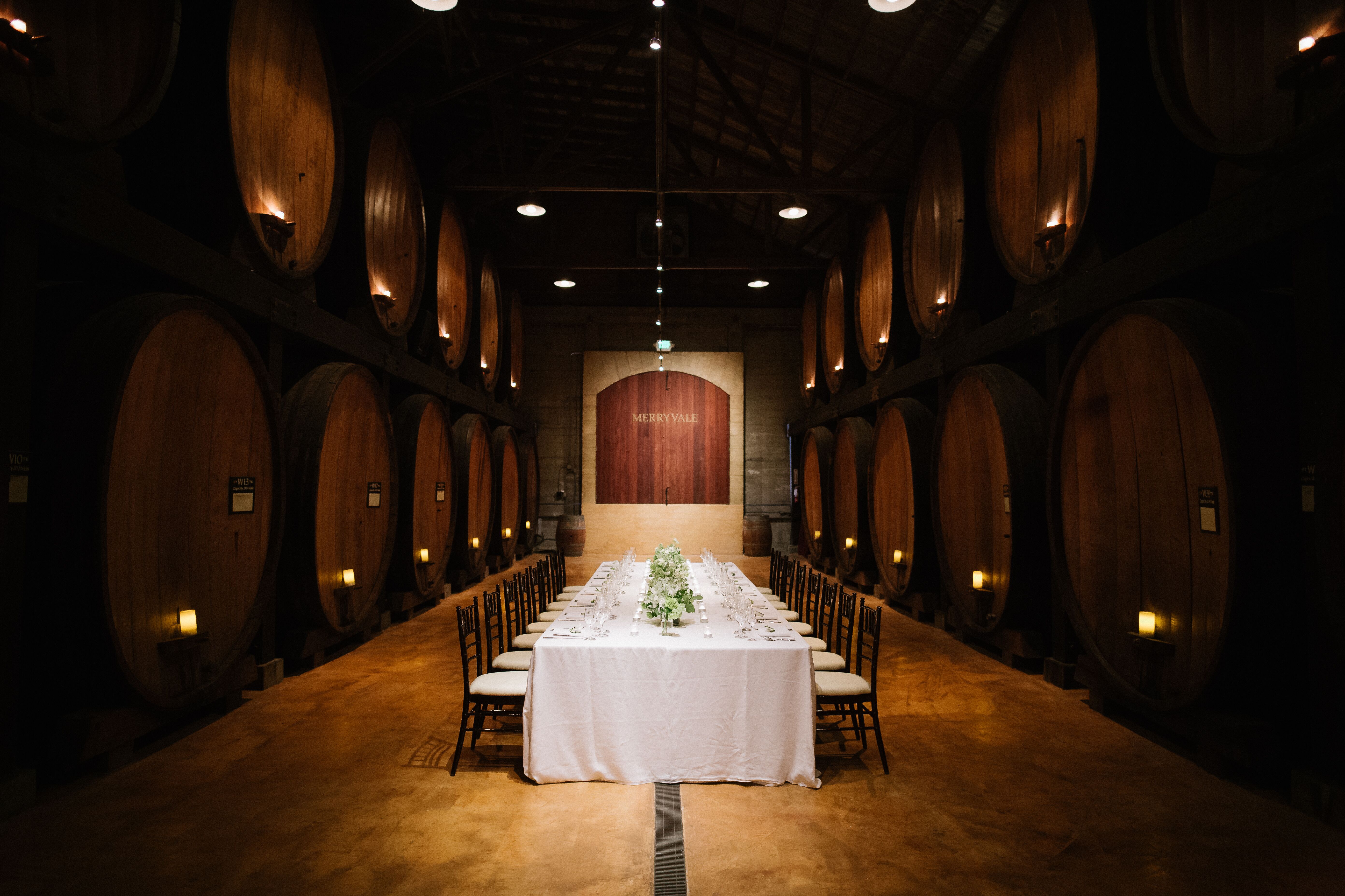 Merryvale Winery wine cellar with long white table set with a floral garland in the middle and chairs on either side