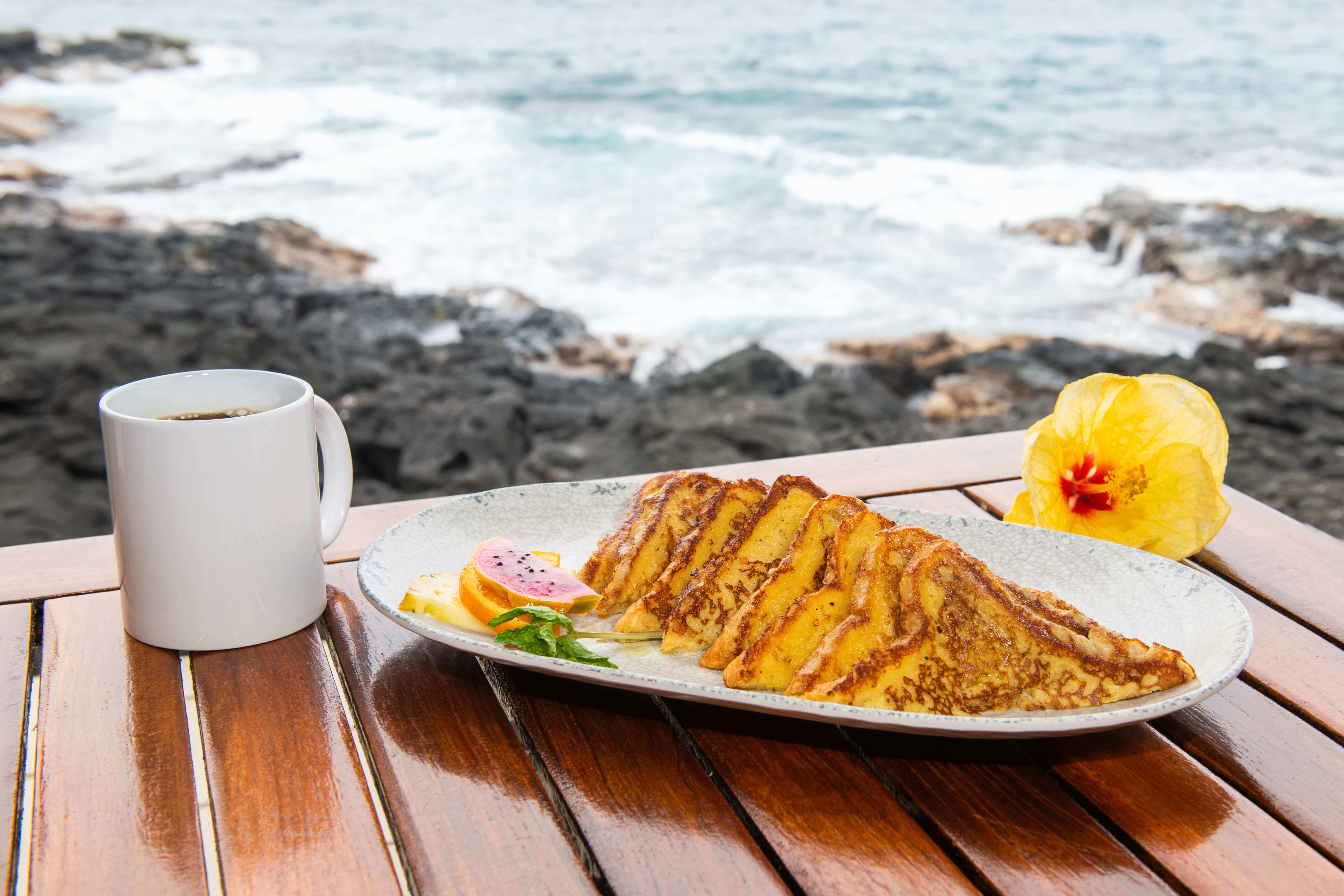 French toast breakfast served with coffee overlooking volcanic rocks and ocean