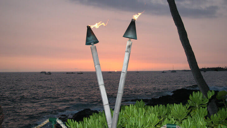two lit tiki torches overlooking the Kailua-Kona Bay
