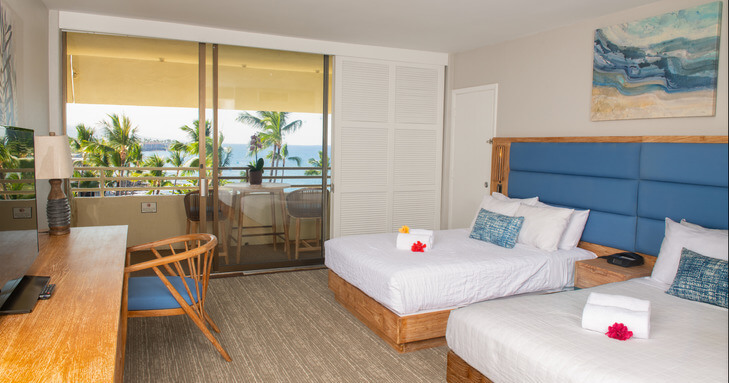 hotel room with palm trees and partial ocean view
