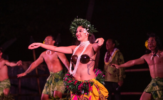 woman with coconut bra and traditional Hawaiian head dress dancing in luau 