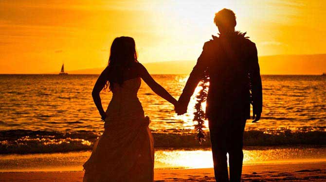 a newlywed couple holding hands during sunset