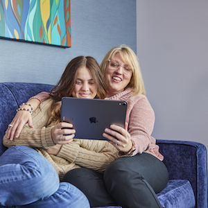 mom and daughter on blue couch with iPad