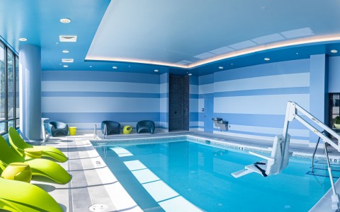 indoor pool with green lounge chairs 