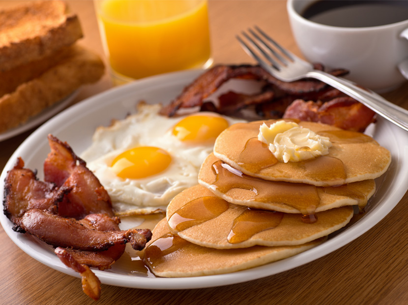 pancakes, bacon, and two fried eggs with coffee and orange juice 
