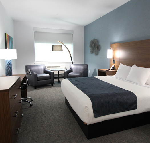 haywardinn rooms standard king bedroom with seating area in the corner with two black chairs