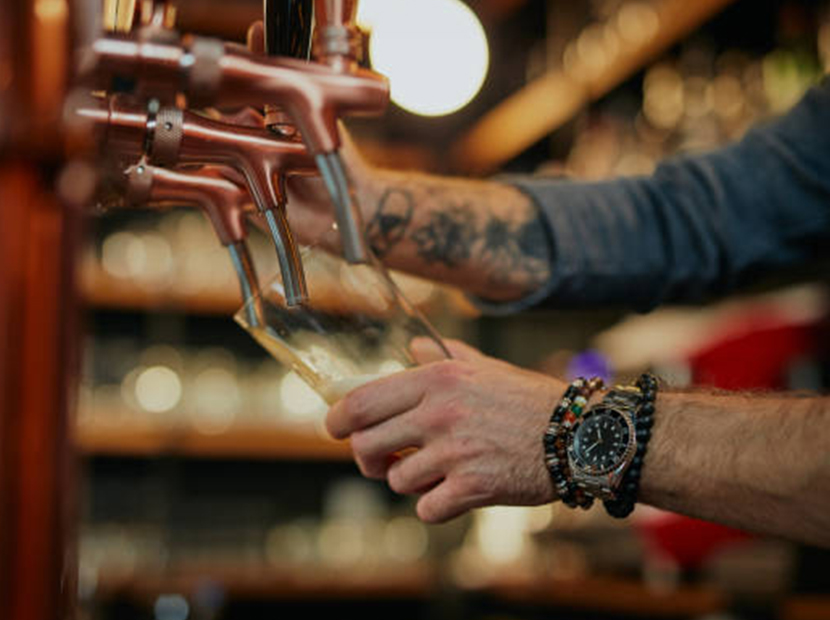 man pouring beer from a tap in a pint glass