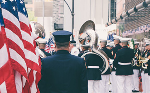 military men in uniform walking down the streets holding the American flag and large instruments