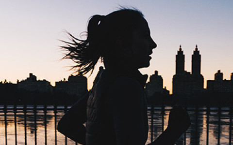 a woman running next to a body of water in central park at dusk