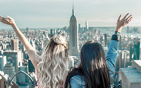 two women standing at the top of the empire state building looking over new york city