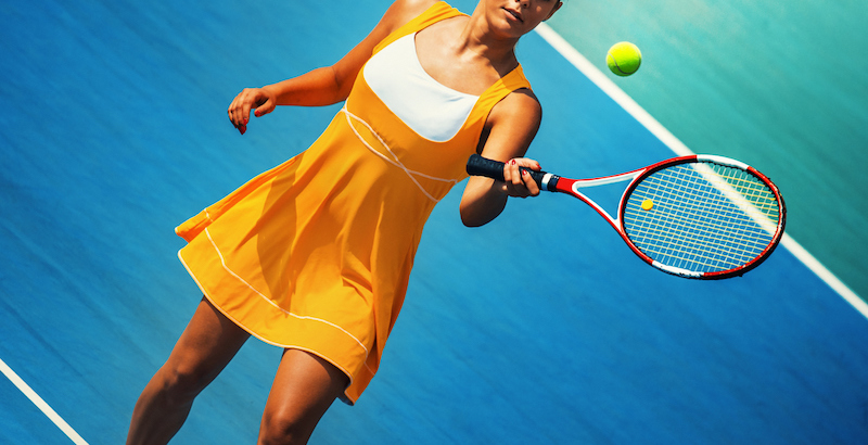 female playing tennis on blue court