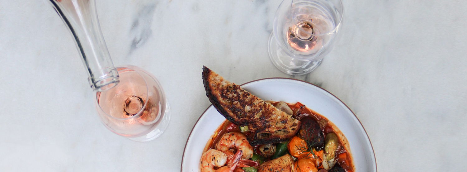 glasses of rosé next to a plate of seafood