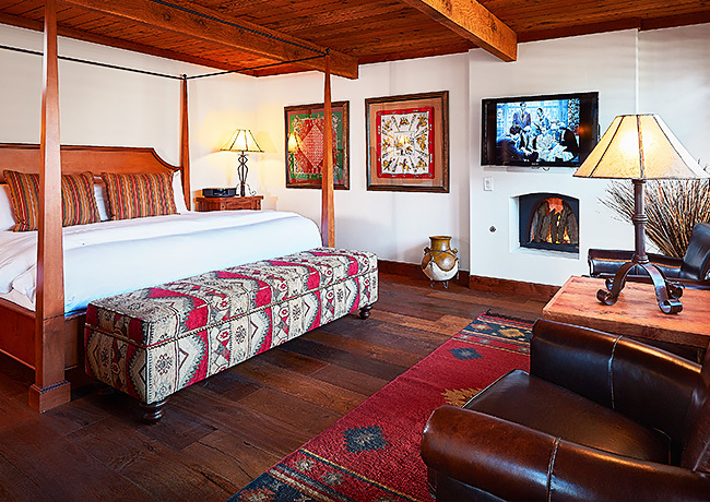 Room with large king bed, across from leather chairs and a window