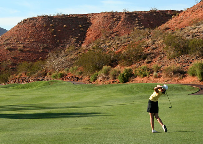 Woman swinging golf club on course