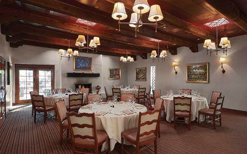 Stetson Dining with round tables drapped in white linen and wood beemed ceilings