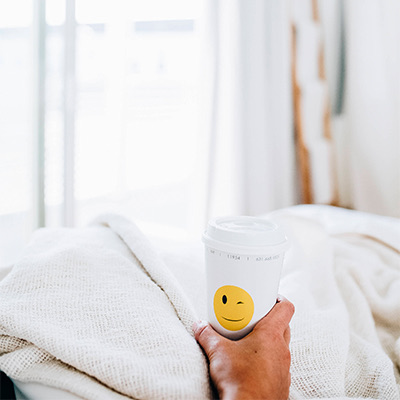 hand golding cup of coffee in bed