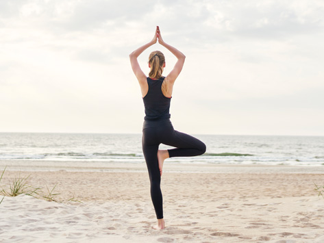 woman doing a yoga pose on the beach